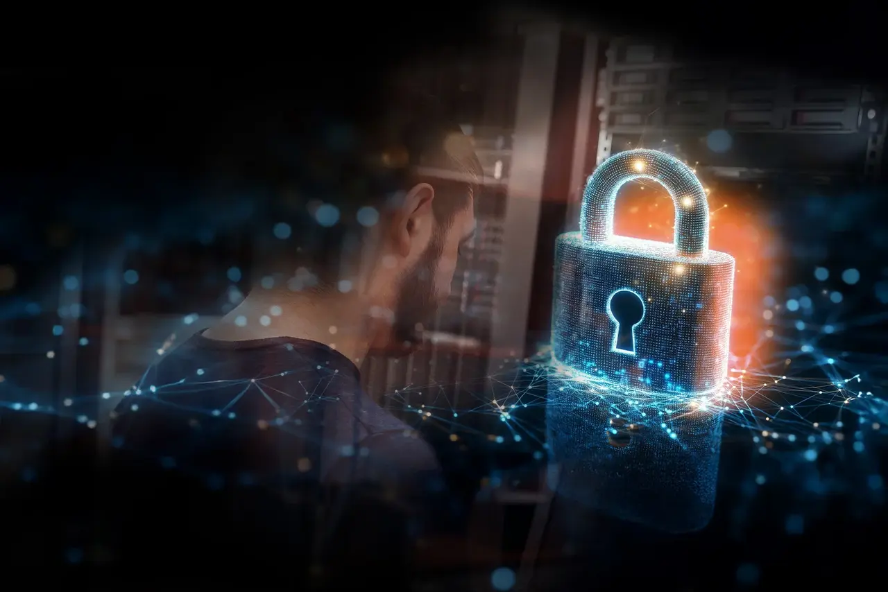 A man is standing in a server room; there is also a large question mark