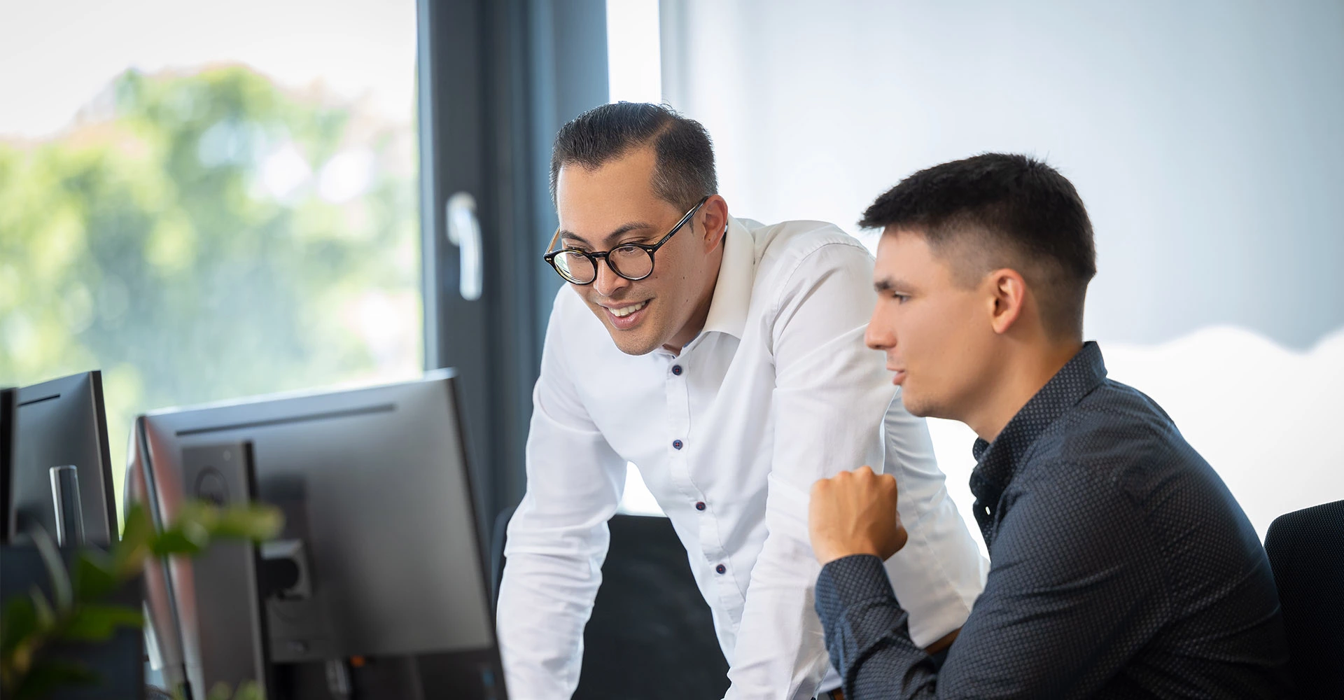 Two persons look at something on a computer