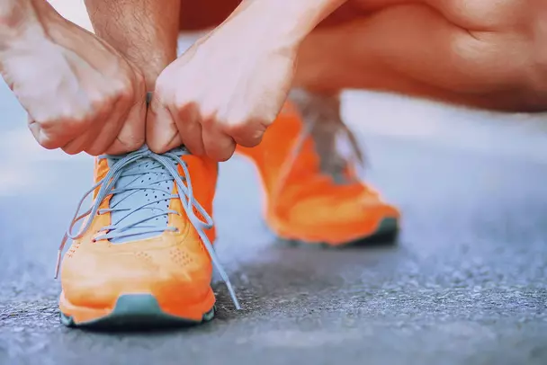 Impulse evening on the topic of self-motivation Man gets ready for the run in his orange-coloured trainers.