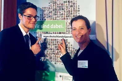 Germany Scholarship 2018/2019 Two people standing in front of the poster for the Deutschlandstipendium event