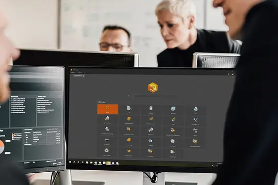 Employees at a workstation, BabtecQ can be seen on the desktop